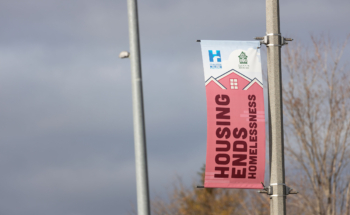 A light pole banner that says "Housing Ends Homelessness"