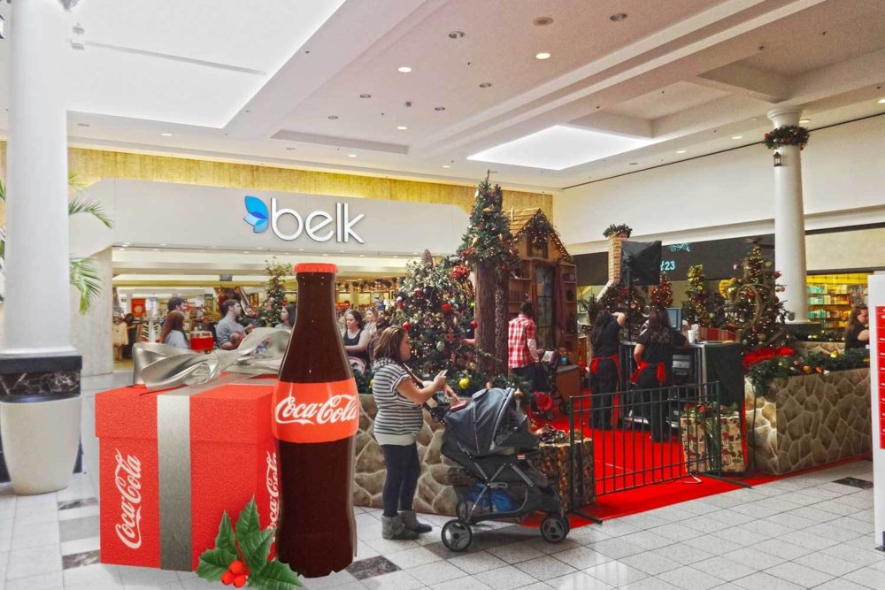 A foam 3d display for Coca Cola inside of a mall with a large Coke bottle and a holiday gift box