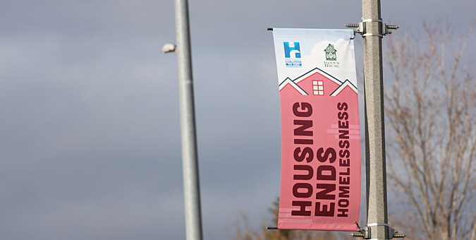 A light pole banner that says "Housing Ends Homelessness"