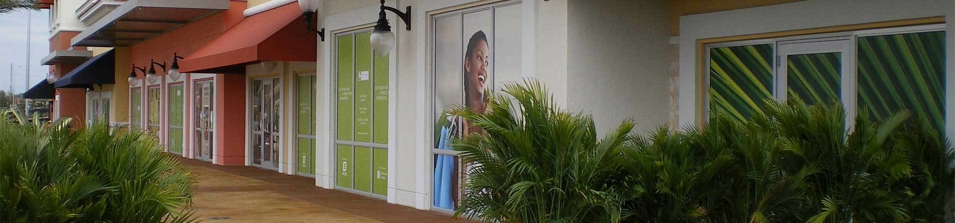 Outdoor adhesive wall graphics promoting retail stores.
